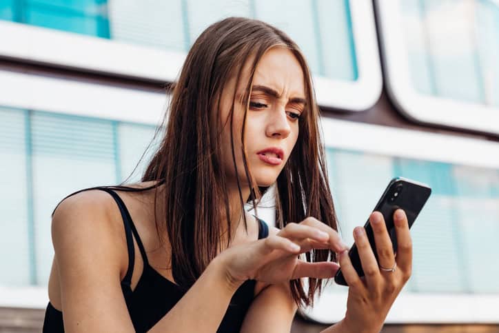 confused woman holding smartphone