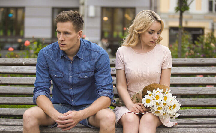 couple sitting on a bench unhappy