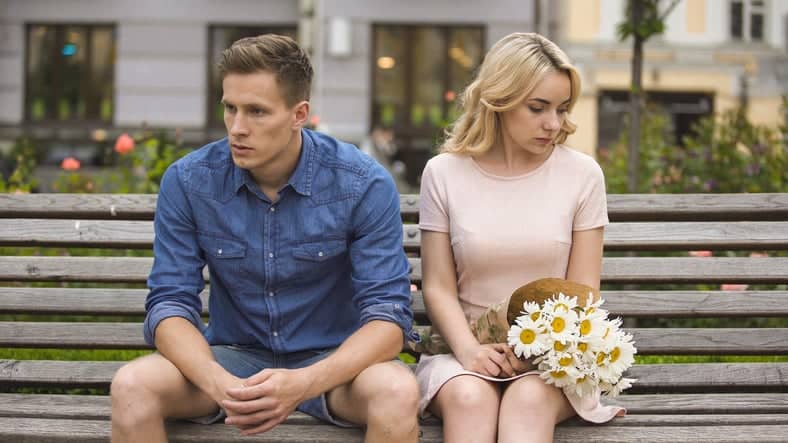 couple sitting on a bench unhappy
