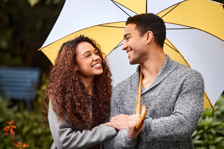Smiling couple under umbrella.