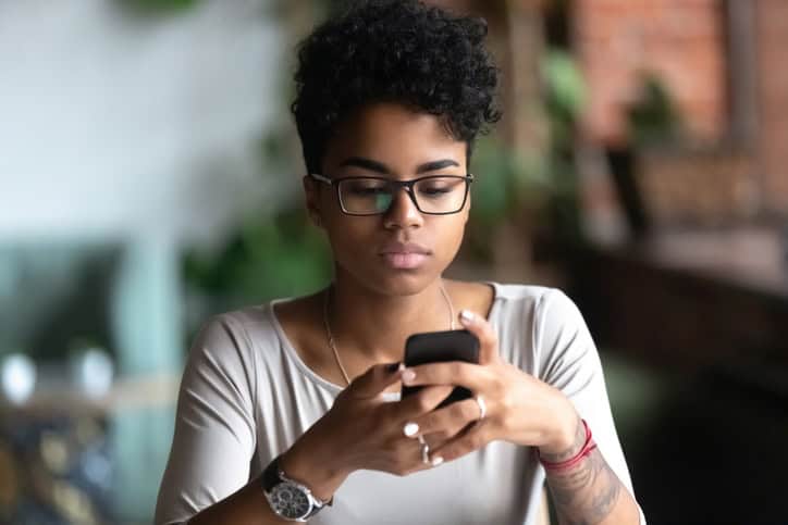 Woman in glasses using cellphone chatting.