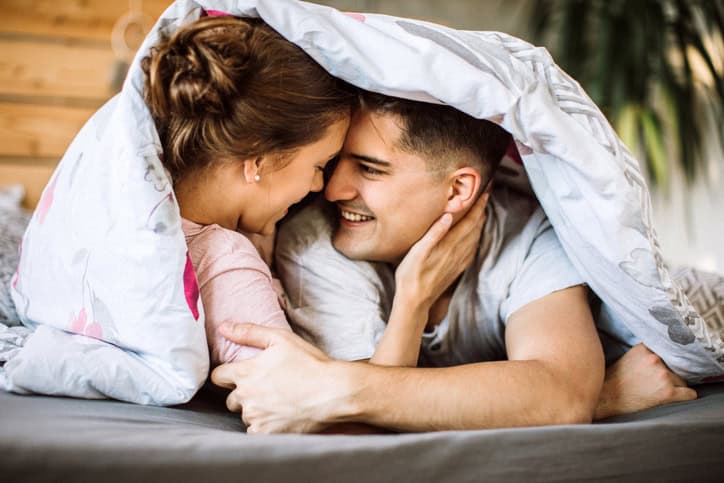 couple smiling at each other under covers