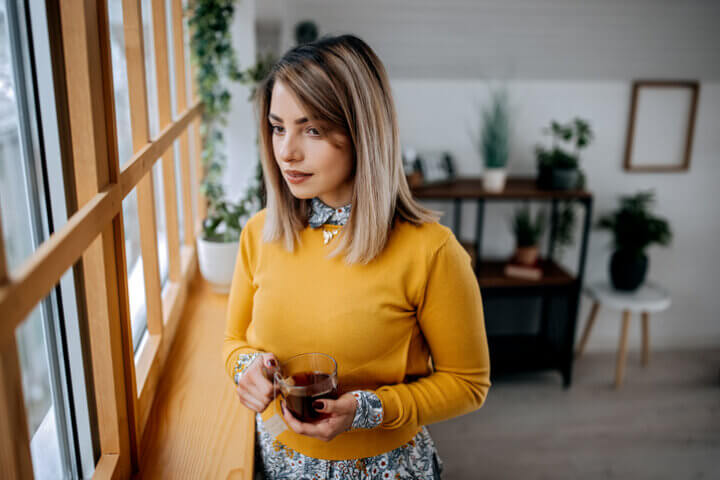 woman looking out window in yellow top