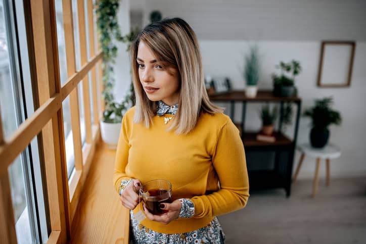 woman looking out window in yellow top