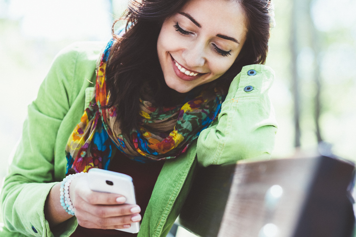 Young woman text messaging outside.