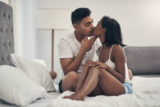 man kissing woman in bed