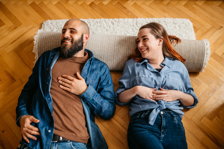 Couple lying down on the floor of an apartment.
