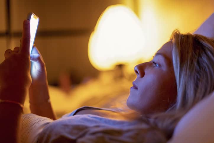 woman texting laying in bed