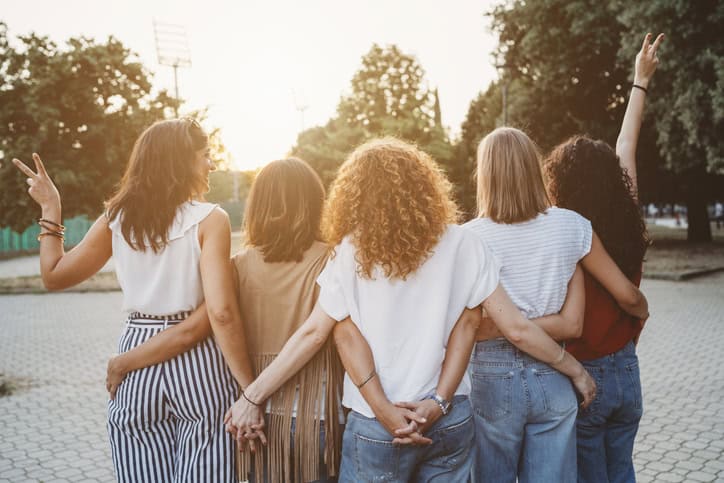 four females back facing camera holding hands