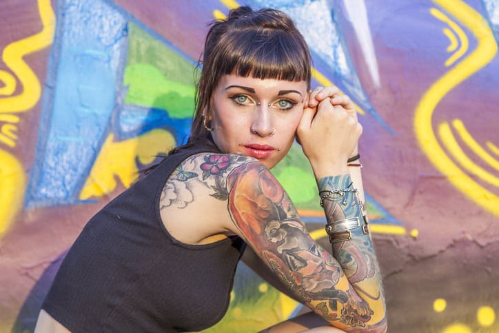 woman with tattoos sitting near grafitti