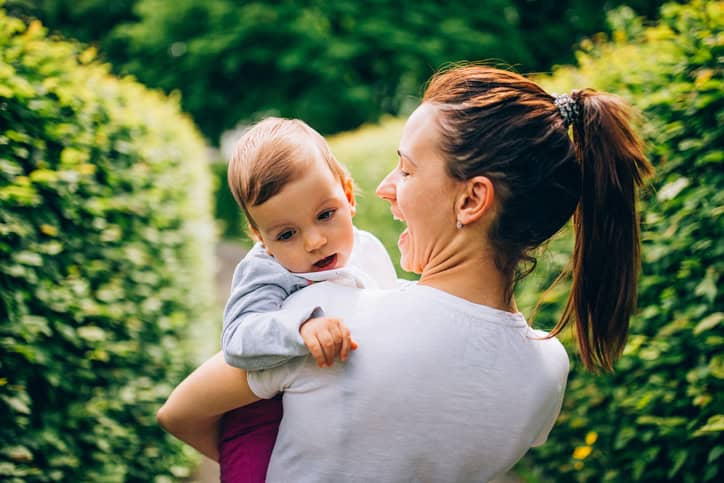 Mom holding child in park.