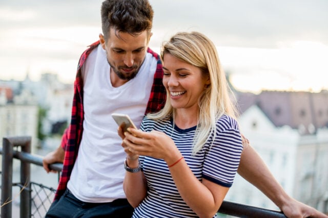 man reading woman's texts rooftop