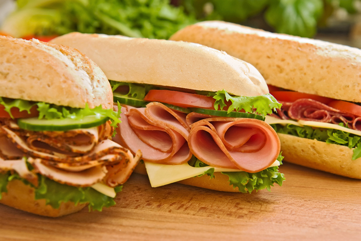 Three sub sandwiches on a cutting board.