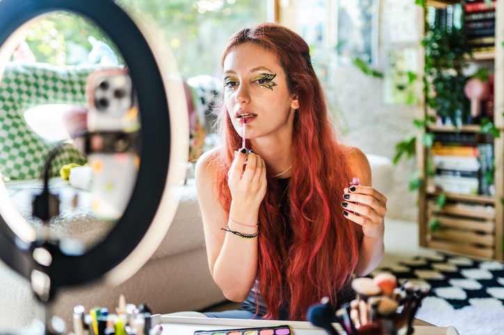 Woman applying makeup in the mirror.