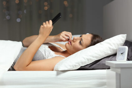 Nervous woman reading phone message at night.
