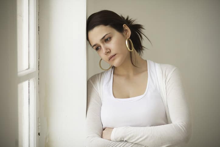 young woman feeling sad beside window