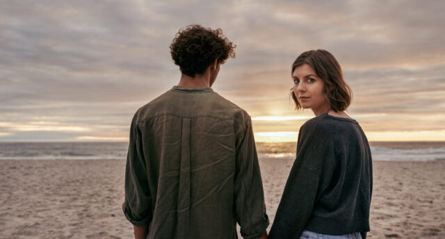 serious couple holding hands on beach
