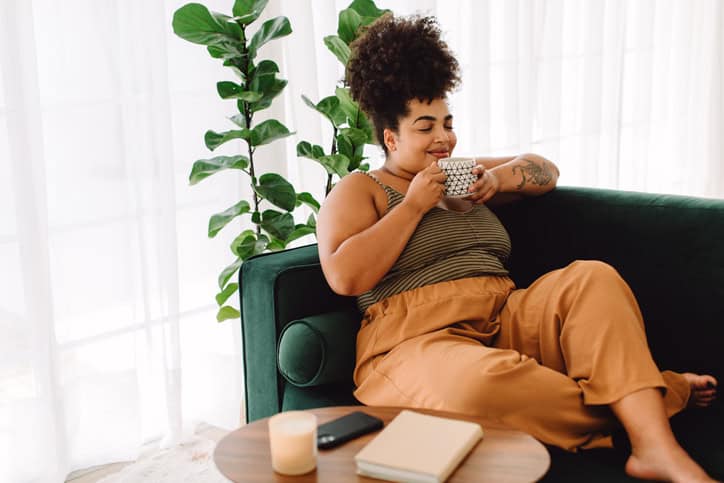 happy woman drinking coffee on couch