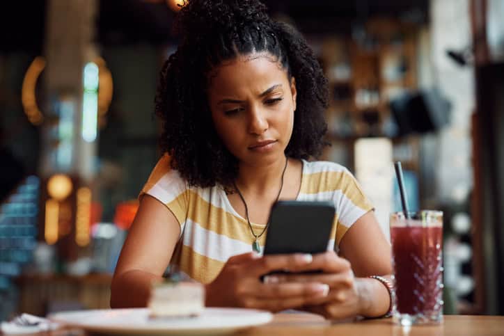 upset woman texting at cafe