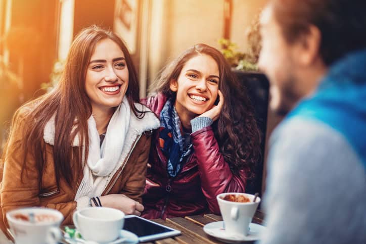 guy chatting to two women at cafe