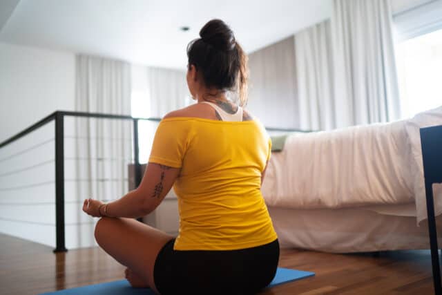 woman meditating on bedroom floor