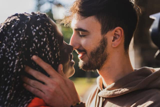 biracial couple kissing in sunshine