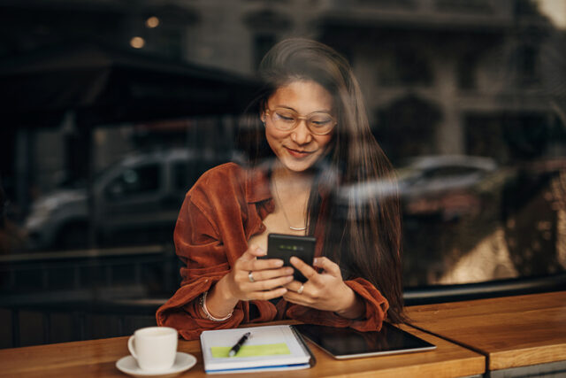 woman texting in cafe window