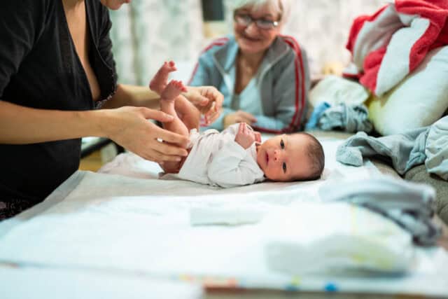 mom changing baby's diaper with grandmom