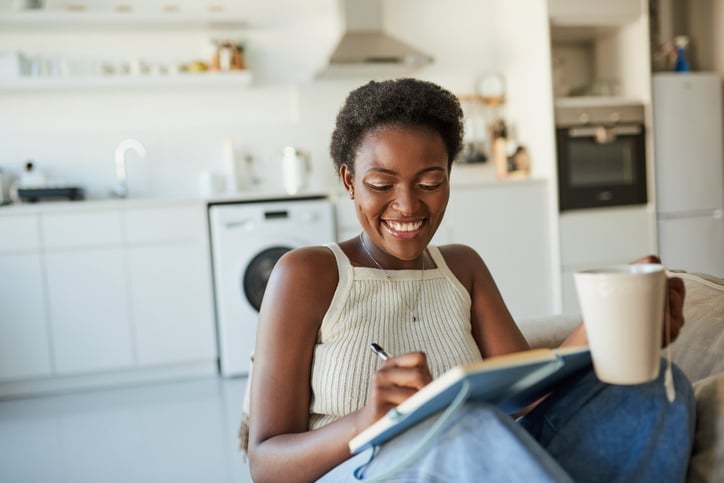 smiling woman journaling with coffee