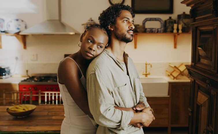 Friends embracing in kitchen.