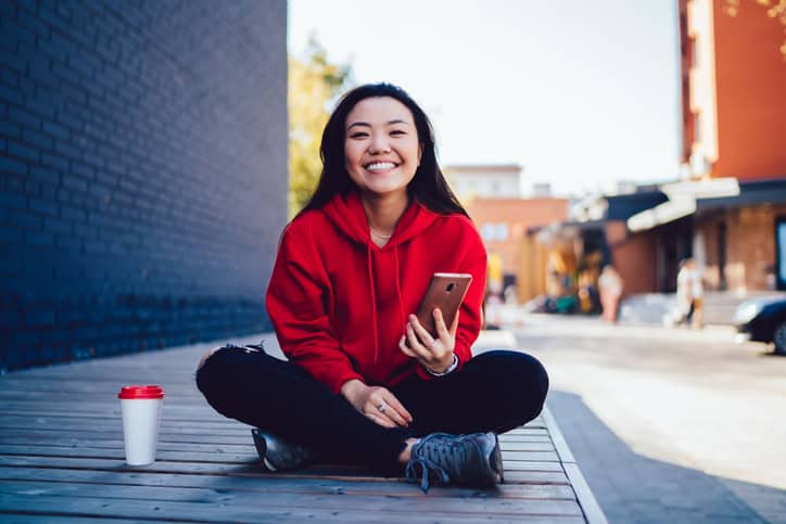 Smiling woman sitting on the pavement.