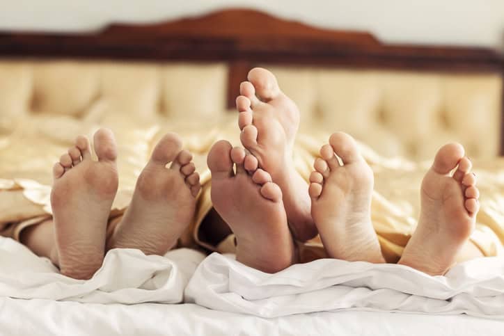 Pairs of feet in bed.