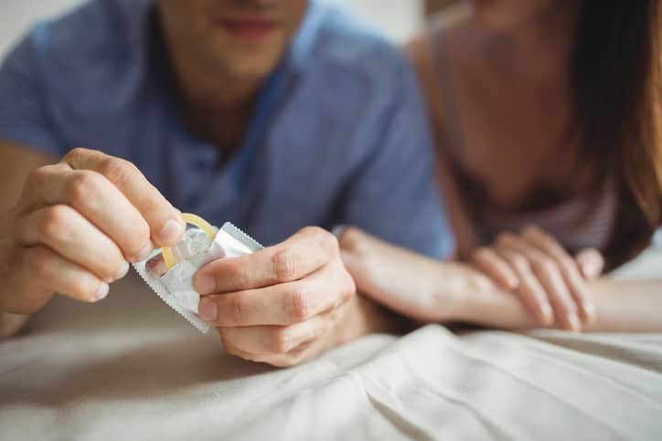 man and woman with condom in bed