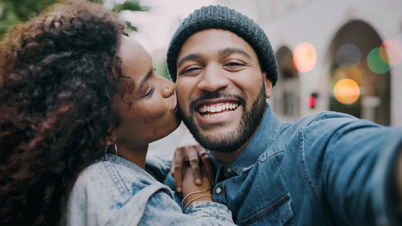 woman kissing smiling boyfriend on cheek