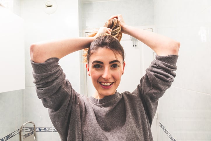 Woman putting her hair in ponytail.