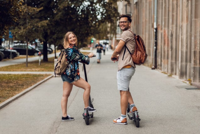 couple riding scooters in city