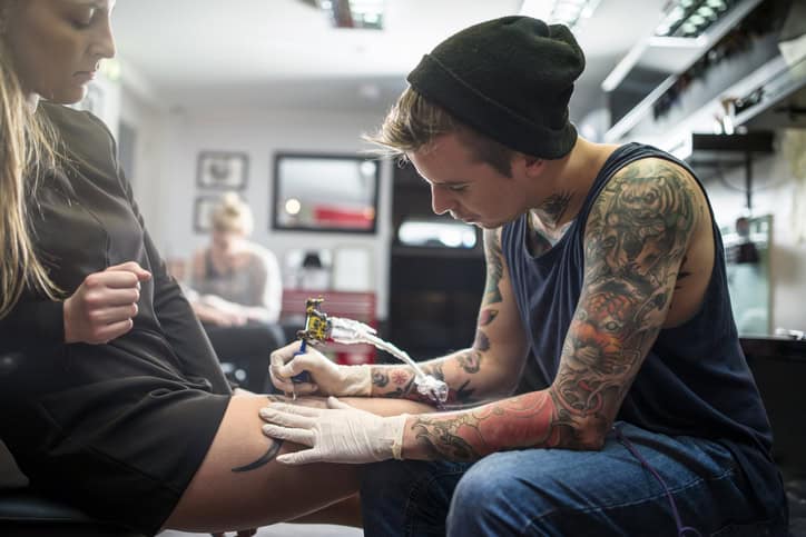 tattoo artist inking up female customer