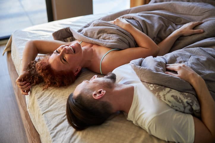 couple smiling in bed after sex