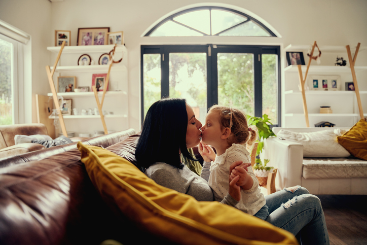 Mom kissing daughter on couch.