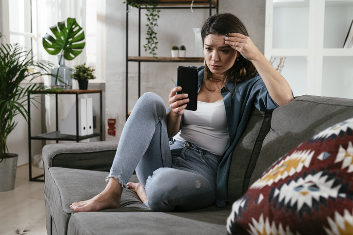 distressed woman reading texts on smartphone