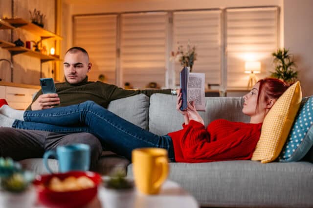 bored couple lounging on couch reading