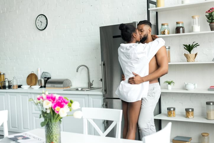 Couple kissing in kitchen.