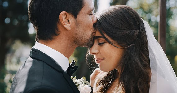 Affectionate young groom kissing his bride.