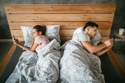 Couple facing away from each other in bed.