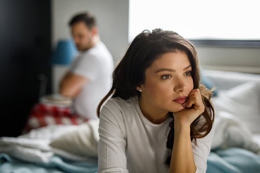 Sad couple sitting on bed after having a quarrel
