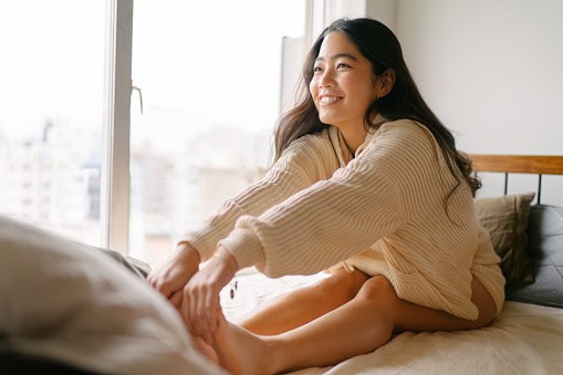 Young woman stretching her legs for the day on her bed