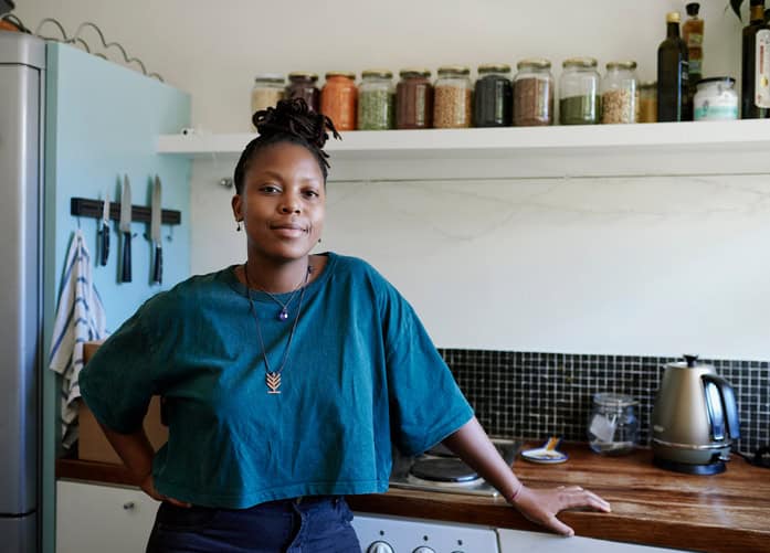 Smiling woman standing in her kitchen.
