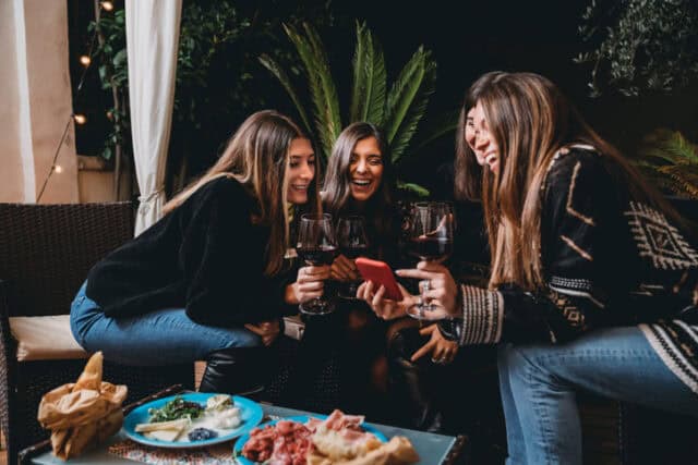 friends laughingn over wine and pizza