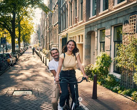 Young couple exploring the city of Amsterdam by bike
