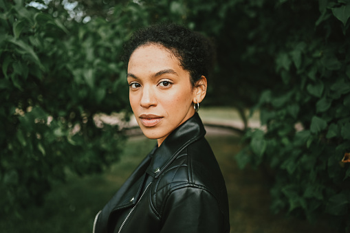 Young woman in black leather jacket posing in nature.
